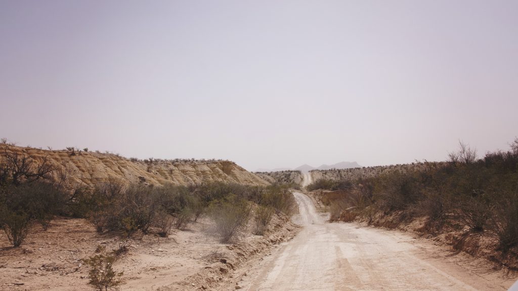 Hazy creamy desert view with the road ahead mountains far off