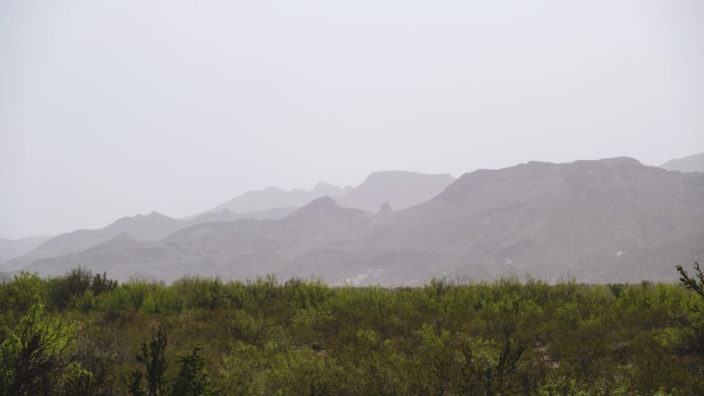 Hazy view of green valley and mountains rising in the distance