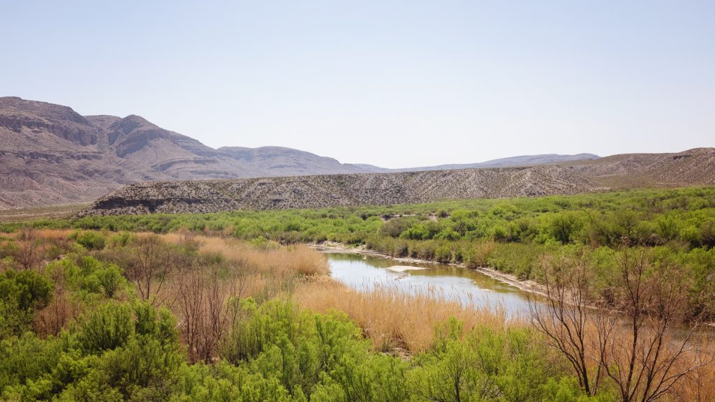 Green river valley in spring with mountains rising above